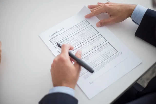 Close-up of a business professional reviewing an application form at a desk. Business licences: eight strategy mistakes that cost you approval